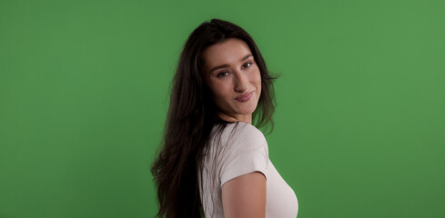 Portrait of a beautiful young woman with long brown hair turning her head and smiling on chroma key...