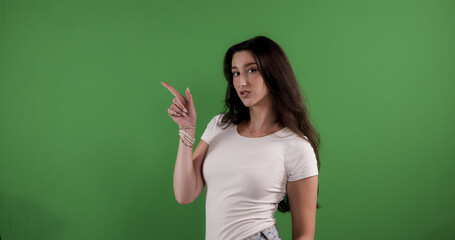 Young woman pointing with index finger to the side on chroma key background