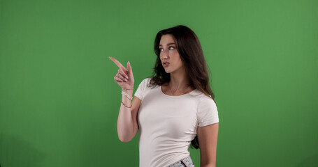 Young woman pointing with index finger to the side on green screen background