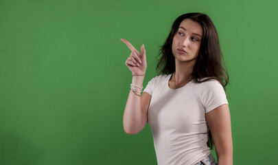 Young woman pointing with finger to the side on green screen background