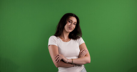 Young woman with arms crossed, looking confident and assertive, on a chroma key background