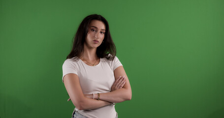 Young woman crossing arms with serious expression on green screen background