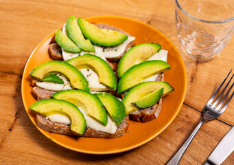 Toast with sliced avocado and cheese served on plate