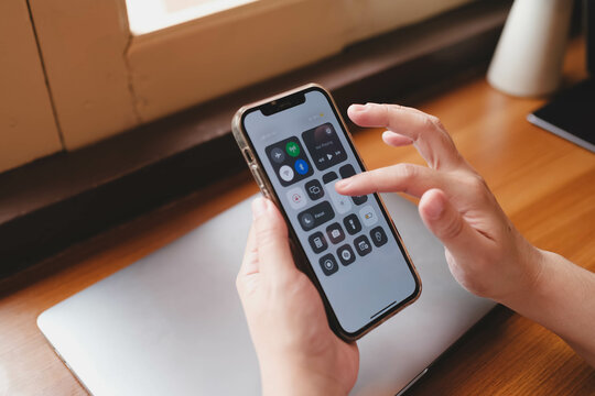 Bangkok, Thailand. July 10, 2025; A person adjusting settings on an iPhone using the iOS Control Center, which provides quick access to system functions like WiFi and Bluetooth.