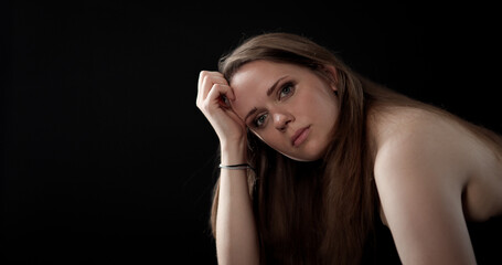 Sad young woman resting her head on her hand, showing loneliness and sadness