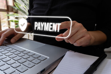 A businesswoman standing in front of her computer points to a virtual button of a shield with a check mark and the word "Payment"