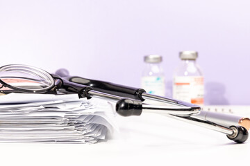 Stacked Medical Documents with Equipment on Desk – Healthcare Concept