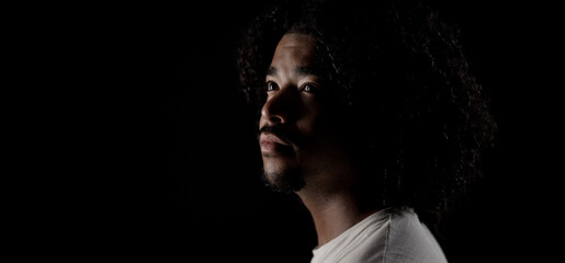 Hopeful african american young man looking up, isolated on black background
