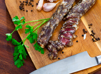 Cured pork sausage with condiments on wooden kitchen table. Preparing food concept.