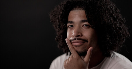 Portrait of a stylish young man touching his chin with a pensive expression