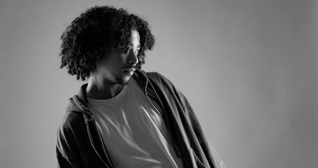 Studio portrait of a young african american man with curly hair wearing casual clothes, looking...