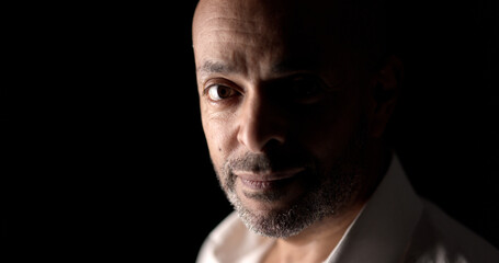 Fototapeta premium Portrait of a middle aged african american businessman with a goatee slightly smiling in a dark room