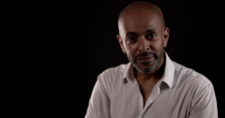 Fototapeta premium Portrait of a middle aged African American man wearing a white shirt on a black background