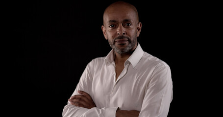 Portrait of a serious african american mature man with crossed arms posing on dark background