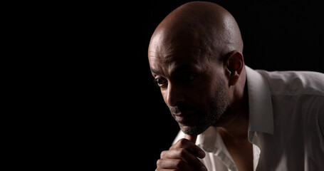 Low key portrait of a thoughtful african american businessman holding his chin, illuminated by a...