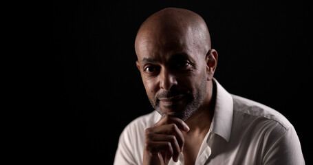 Obraz premium Studio low key portrait of confident African American businessman posing with hand on chin