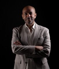 Studio portrait of a smiling African American businessman crossing his arms, exuding confidence and...
