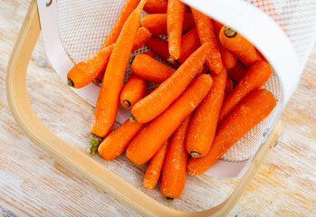 Raw carrots in bucket on wooden background, ingredients for cooking at home