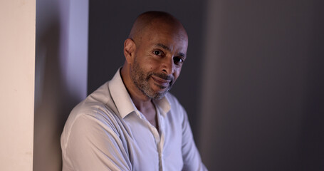 Obraz premium Portrait of a smiling African American businessman leaning against a wall, conveying confidence and professionalism