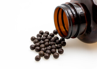 Chinese Herbal Medicine Pills Spilled from Brown Glass Bottle on White Isolated Background &ndash; Traditional Asian Medicinal Pills