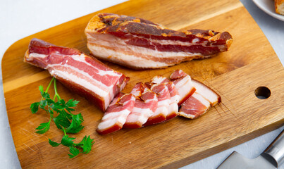 Smoked lard. Delicious pork belly with parsley on a wooden surface at kitchen