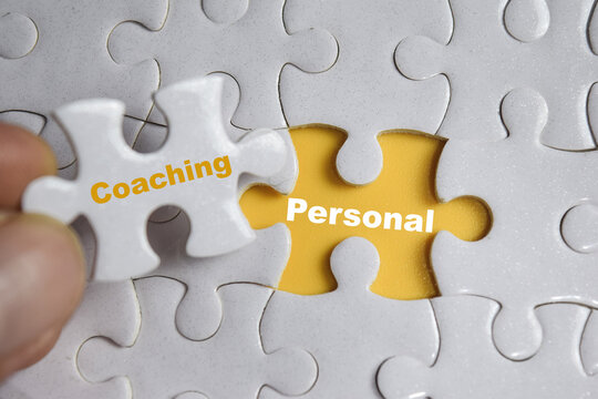 Hand holding piece of jigsaw puzzle with word Coaching or personal. Business and finance concept