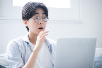  パソコンを見ながらビックリと驚く男性の困る悩むの表情