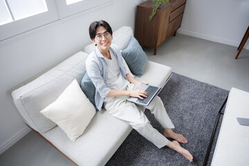 リビングでパソコンをする男性の俯瞰のカメラ目線