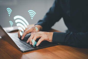 Businessman using laptop with floating Wi-Fi icons, symbolizing wireless internet connection,...