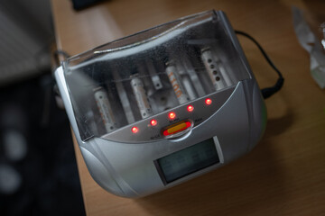 Battery charger for AA batteries on a table, captured in natural indoor light, highlighting the...