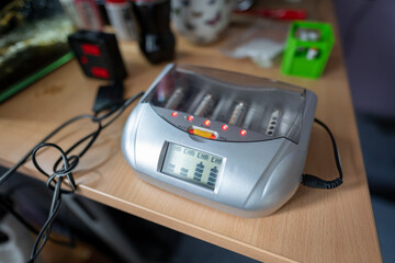 Battery charger for AA batteries on a table, captured in natural indoor light, highlighting the compact design and functional setup in a home environment.