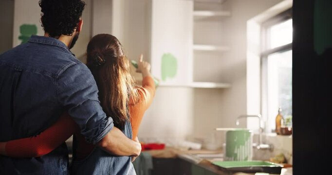 Couple, choice and hug with painting for kitchen renovations, upgrade and maintenance. New home, man and woman back for DIY, makeover and decoration decision with creative homeowner and art tools