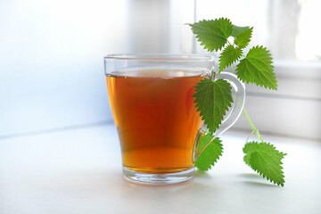 Cup of tea, decoction with fresh stinging nettle. Alternative medicine. Herbal tea. Detox. Homeopathy medicine remedies. Space for text