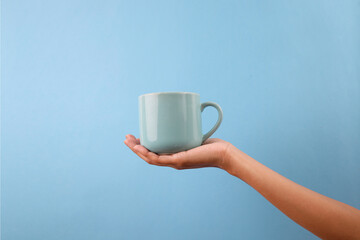 Hand Presenting Light Blue Mug Isolated On Blue Background