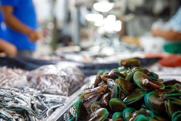Asian fish market, display of fresh green mussels and seafood on stall