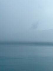Misty seascape on a foggy day. Calm water and sky blending on the horizon. Minimalist and...