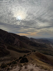 Mountain landscape with a dramatic cloudy sky. View from a hiking trail over dry hills and valleys. Scenic nature background for travel and adventure.