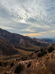 Scenic mountain landscape with a vast valley under a dramatic cloudy sky. Expansive view of rolling...