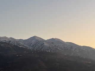 Snow capped mountain peaks against a clear twilight sky. Scenic mountain range landscape at dusk...