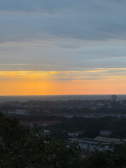 Scenic view of a coastal city at sunset. Urban skyline silhouette against an orange sky over the ocean. Beautiful twilight landscape.