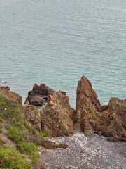 Rugged rocky coastline with steep cliffs and a pebble beach. Scenic view of the ocean from a high...