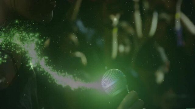 Singer raising mic, singing on stage, green particle spiral forming around grille enhancing vocals
