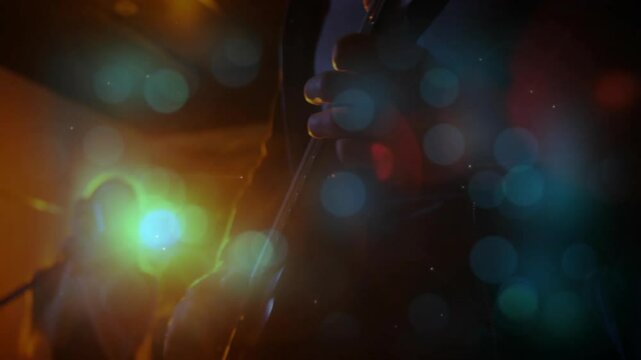 Drifting blue orbs parting bandmates playing guitar singing into mic on amber-lit stage to perform