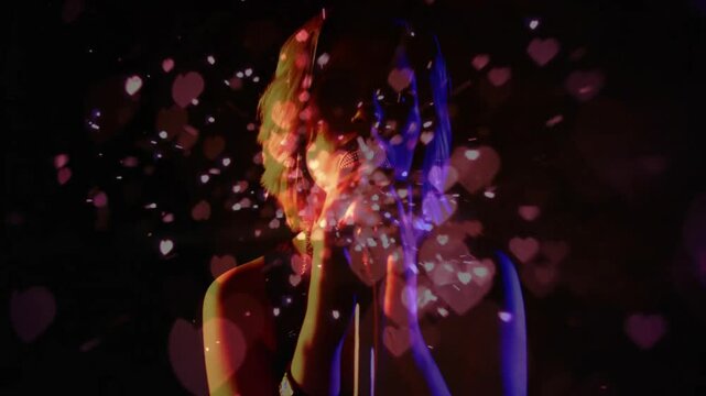Floating hearts drifting across frame, teen singer gripping mic leaning in colored lights music gig