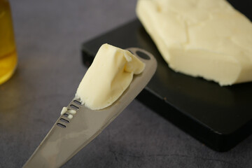 Butter being spread with a knife on a dark cutting board
