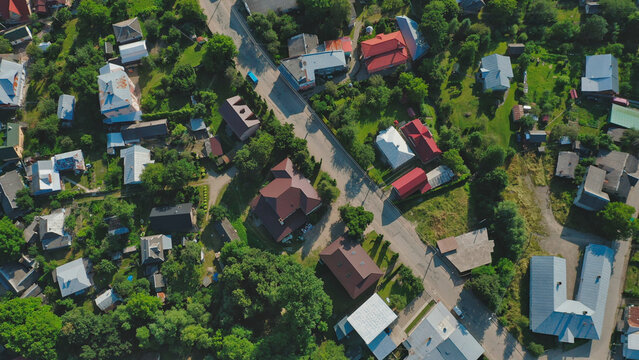 Top view of a vibrant village showcasing houses and green landscapes under bright sunlight