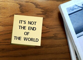 Vintage table with note written - It's not the end of the world - means not the worst thing that could happen - consequences of situation not bad as might seem at first