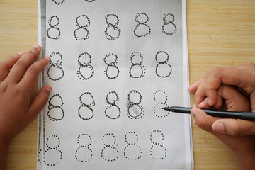 Child practicing number eight writing with dotted lines