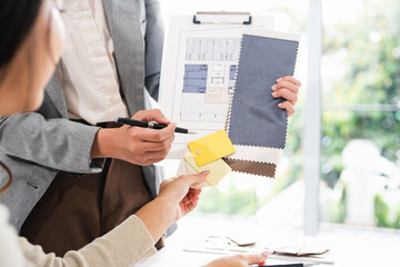 Close up on hands of Experienced Interior designer holding color palette pantone samples and...