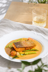 Salmon steak with asparagus in bisque sauce, bright natural lighting, overhead composition